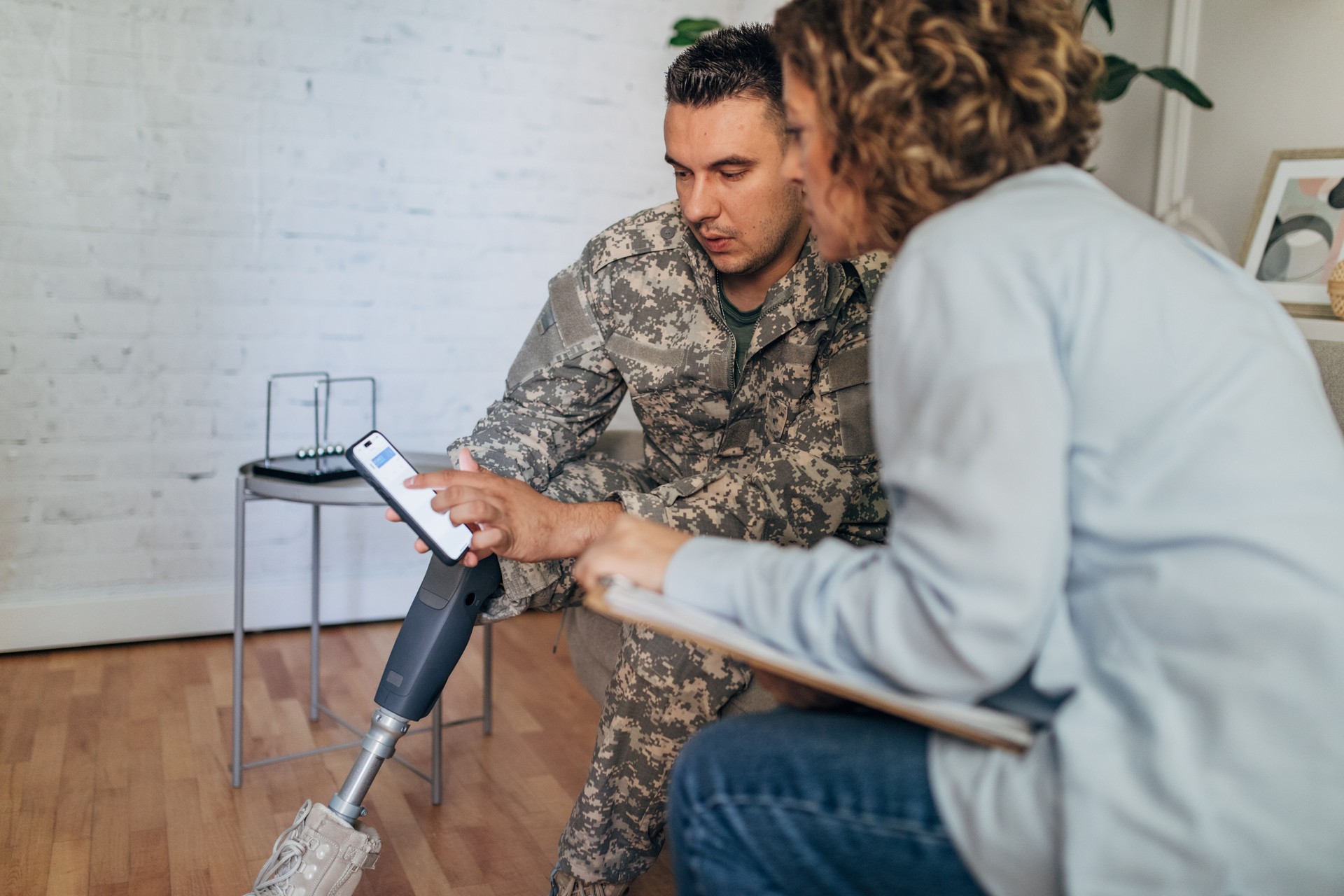 Military veteran with a prosthetic leg and therapist using smartphone together